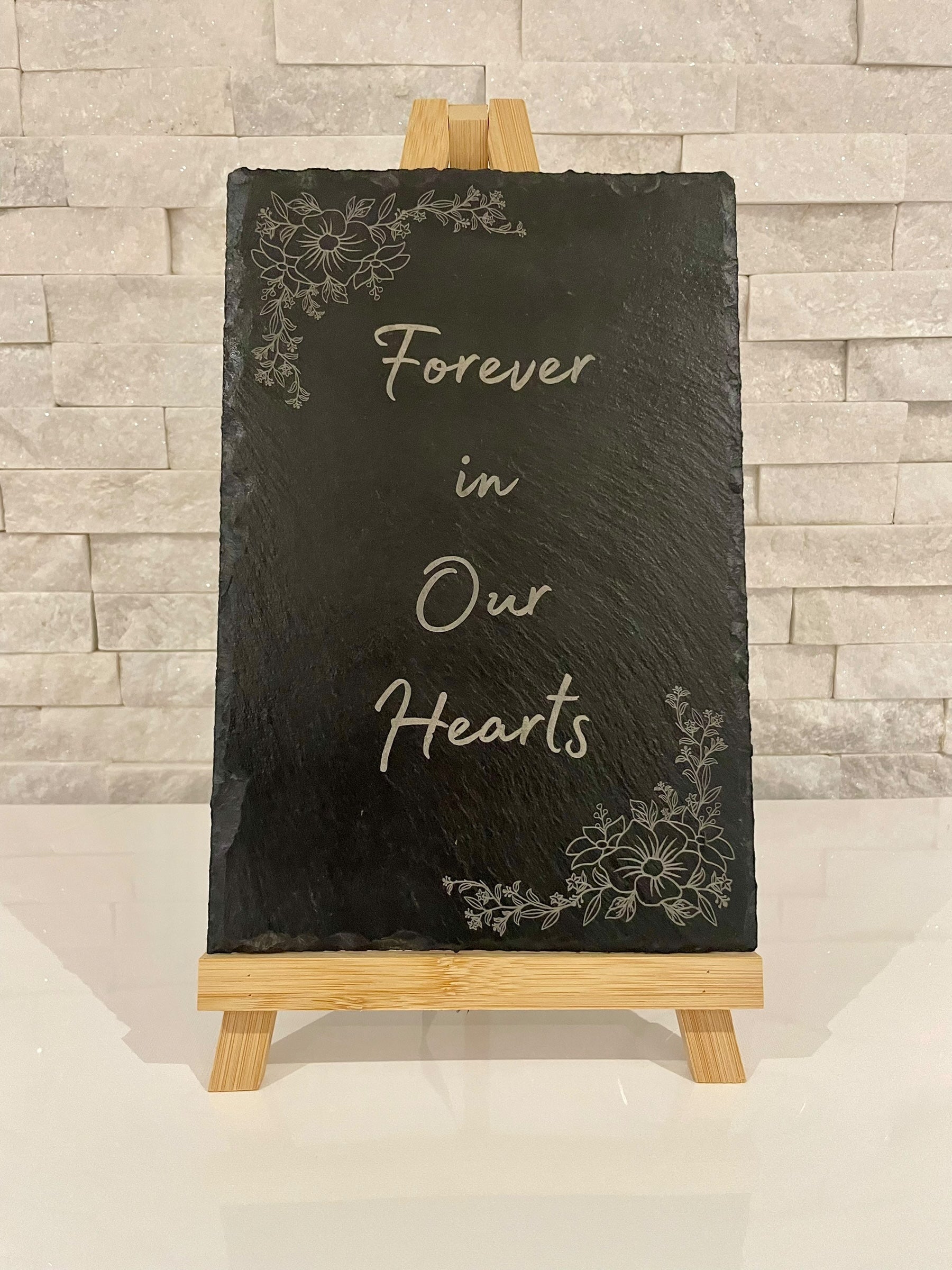 Personalised engraved memorial slate sign displayed on a funeral remembrance table with custom wording and optional floral corner design.